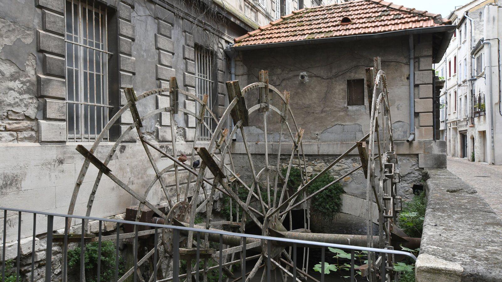 Weathered wooden water wheels standing over the narrow canal on Rue des Teinturiers