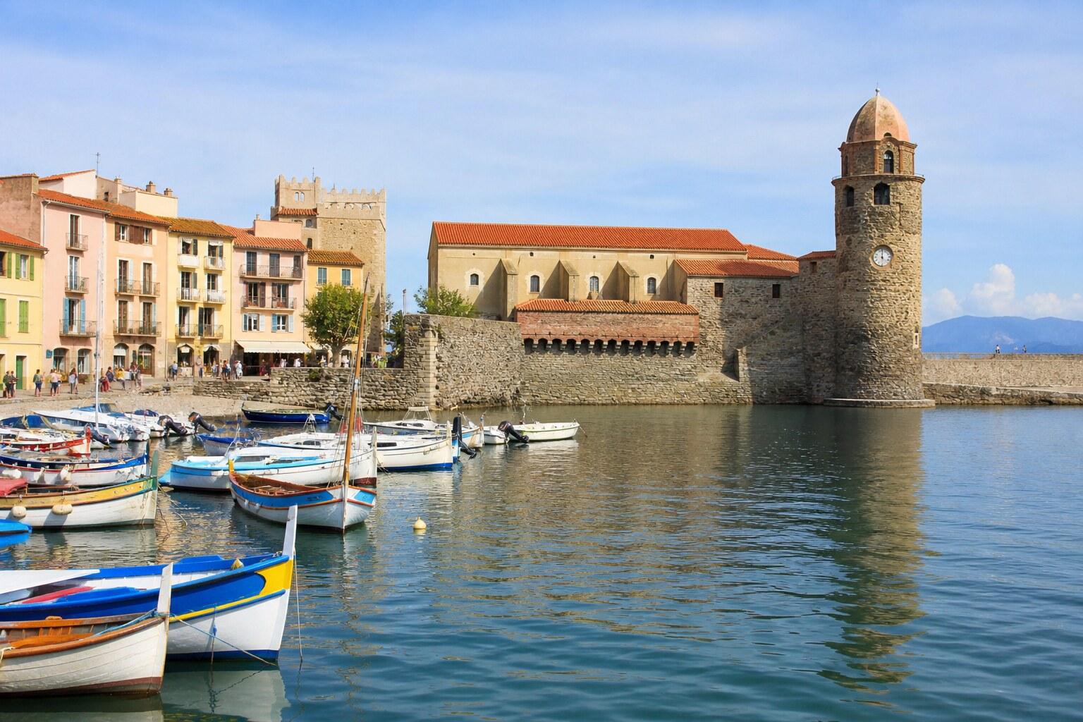 Colorful boats in Collioure harbor below the waterfront church and fortifications