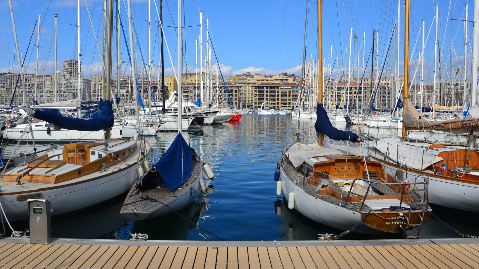 Sailing boats moored closely together in the Vieux-Port under a clear blue sky