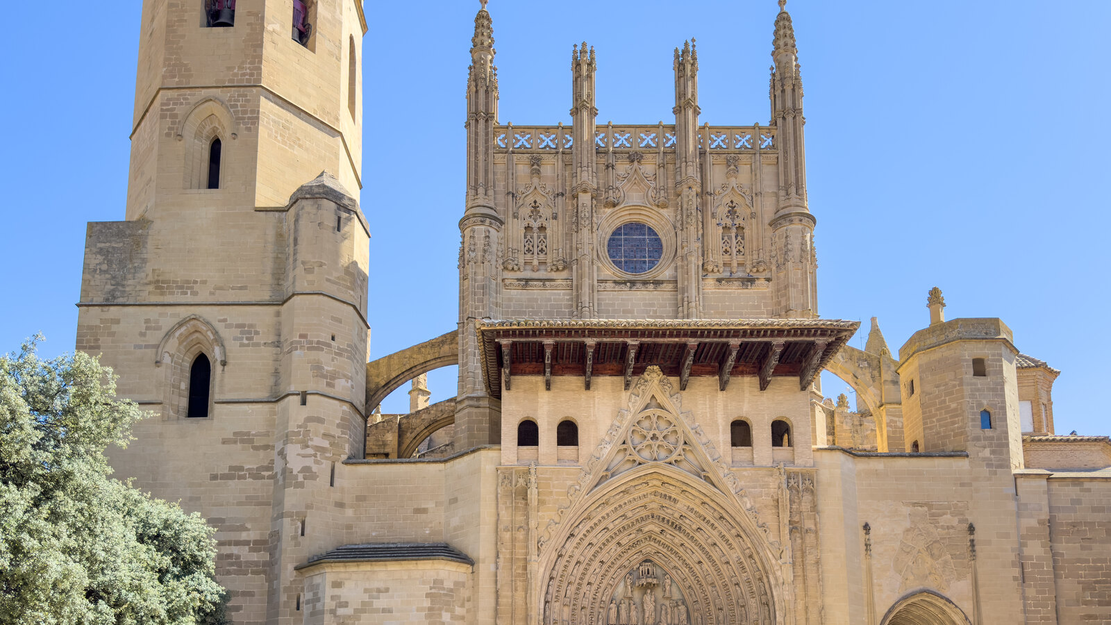Stone Gothic façade and bell tower of Huesca Cathedral against a clear blue sky